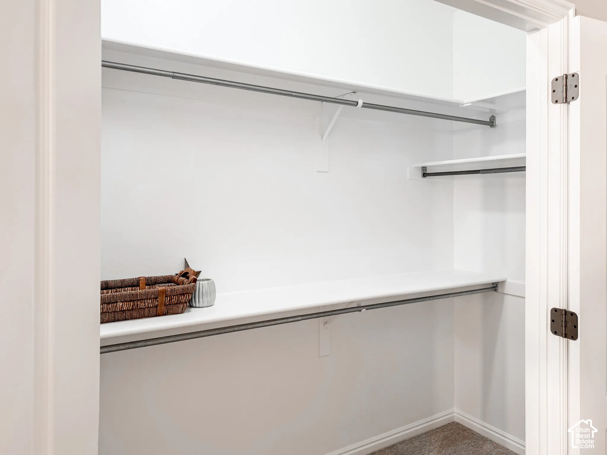 White-painted closet featuring multiple shelving units and metal hanging rods