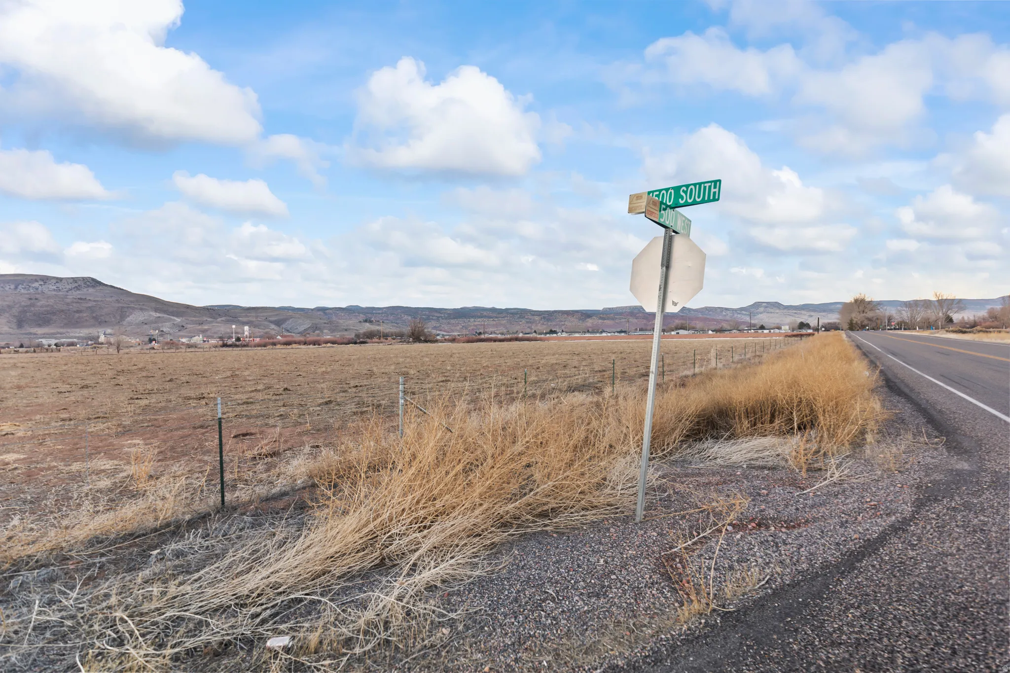View of asphalt road featuring a mountain view, a view of rural / pastoral area, and traffic signs