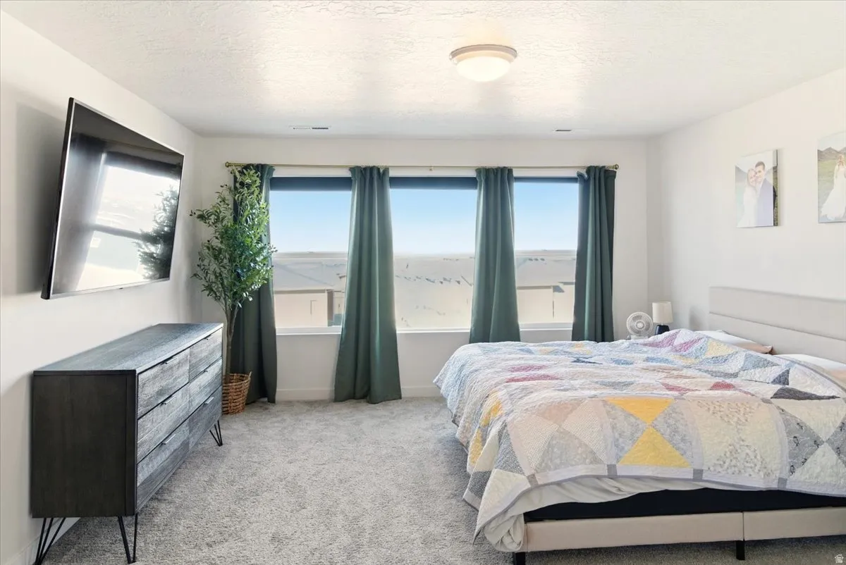 Bedroom with multiple windows, carpet flooring, and a textured ceiling