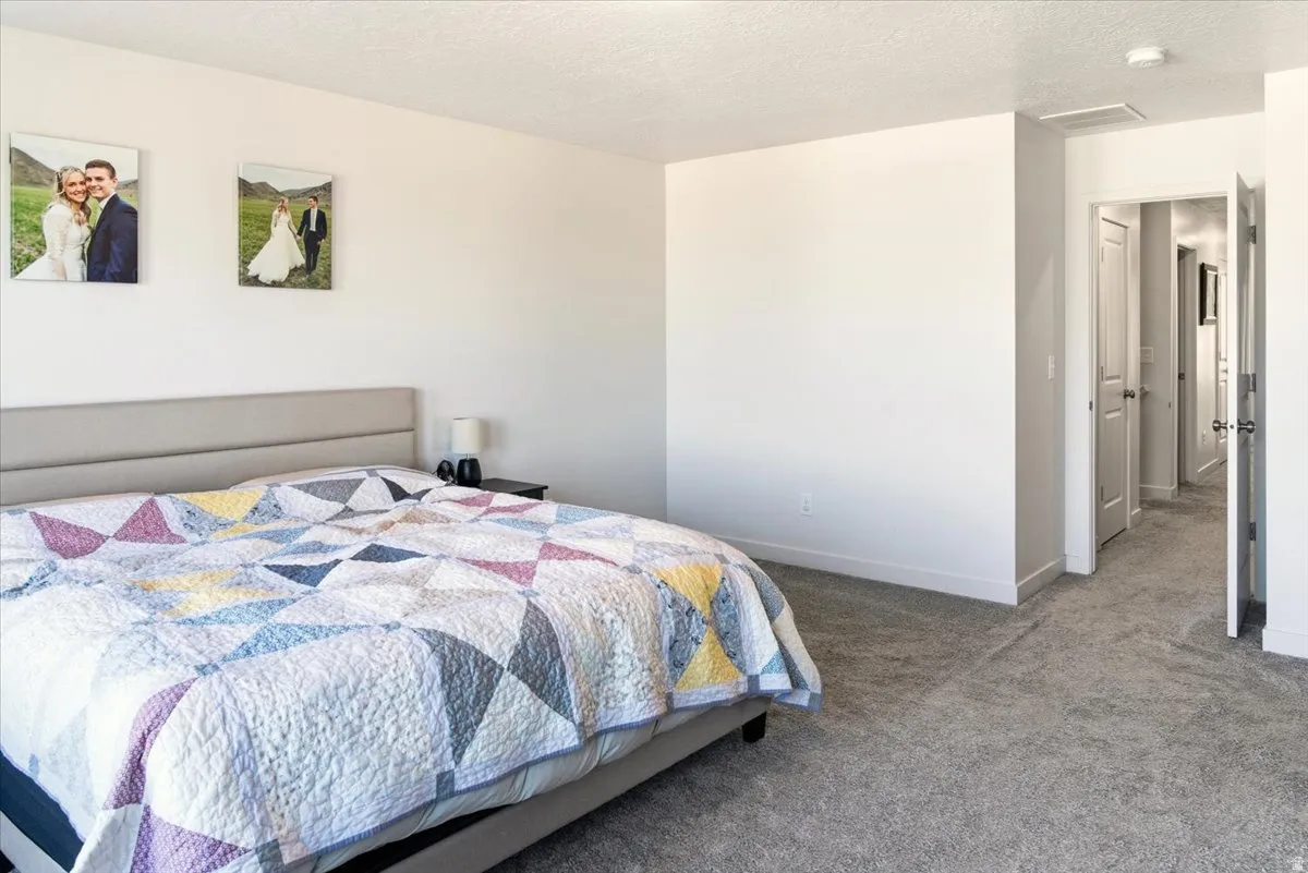 Carpeted bedroom with a textured ceiling and baseboards