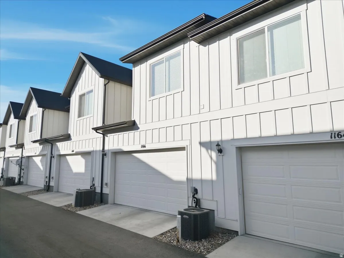 View of home's exterior with board and batten siding, a residential view, a garage, and driveway