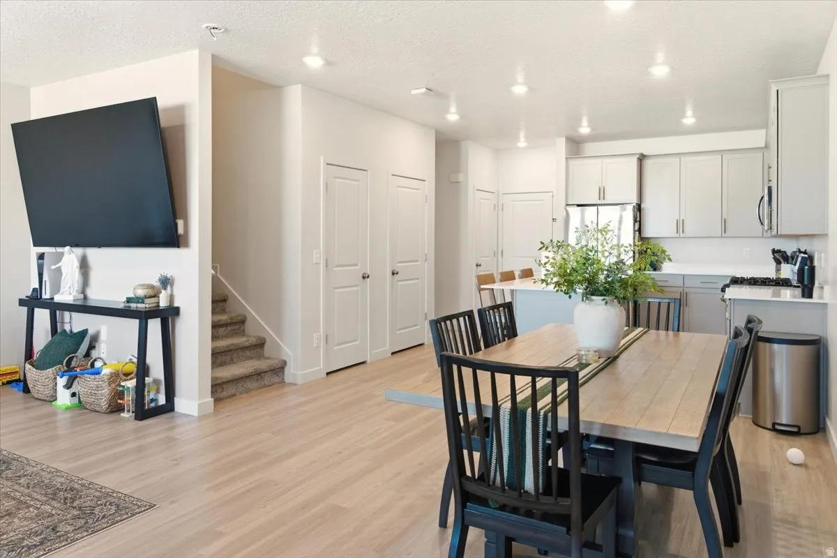 Dining area featuring stairway, light wood-style floors, a textured ceiling, and recessed lighting