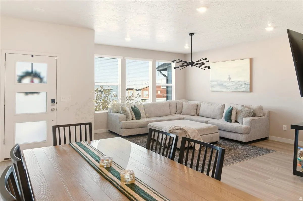 Dining area with light wood finished floors, a chandelier, recessed lighting, and a textured ceiling