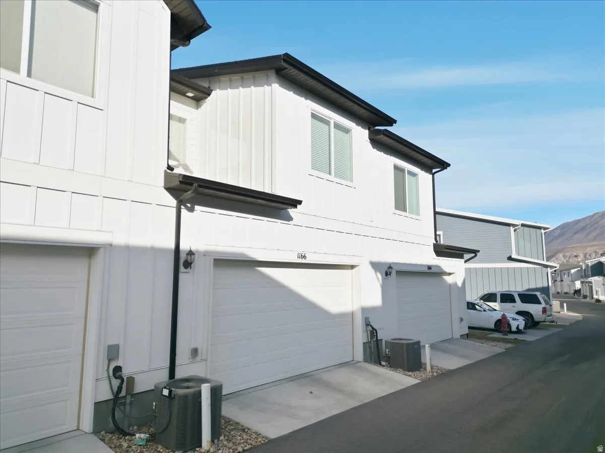 View of property exterior with board and batten siding, a garage, concrete driveway, and a mountain view