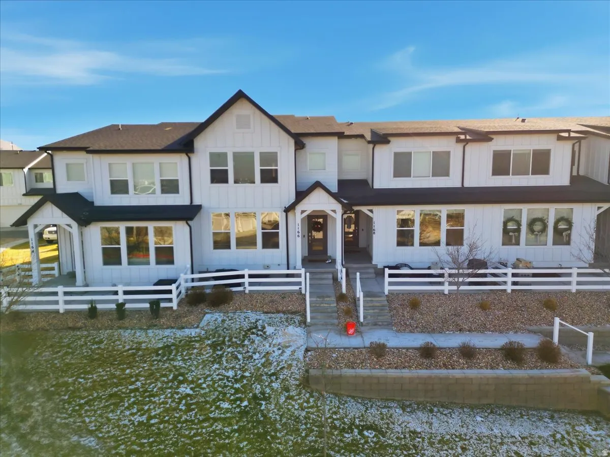 View of front of house with board and batten siding, a fenced front yard, and a shingled roof