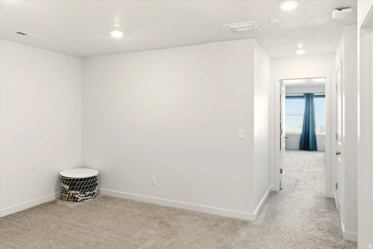 Unfurnished room with light colored carpet, a textured ceiling, and recessed lighting