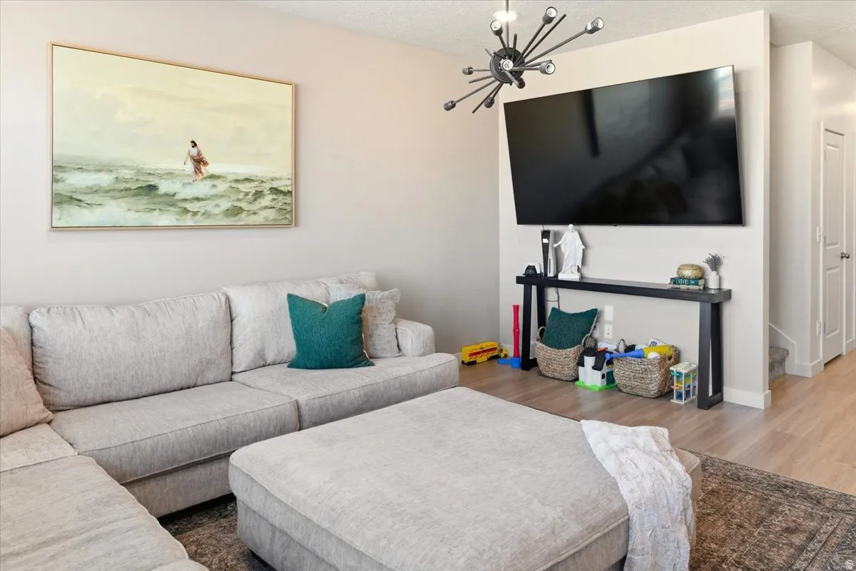 Living room featuring wood finished floors, a chandelier, and a textured ceiling