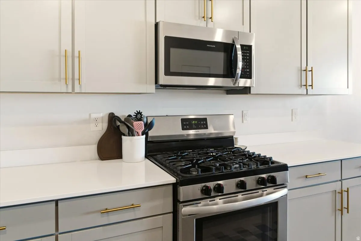 Kitchen featuring stainless steel appliances, gray cabinetry, and light stone counters