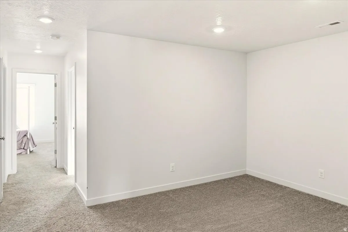 Unfurnished room featuring light colored carpet and a textured ceiling