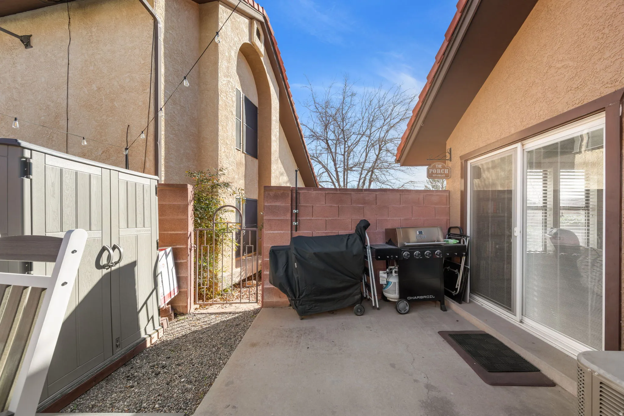 View of patio with a gate and area for grilling
