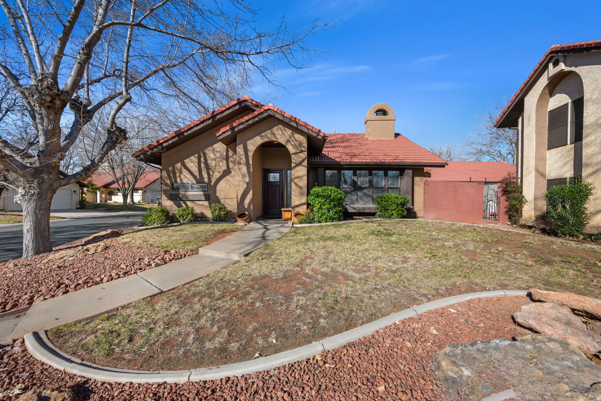 Mediterranean / spanish-style home featuring a tile roof, a chimney, stucco siding, and a front yard