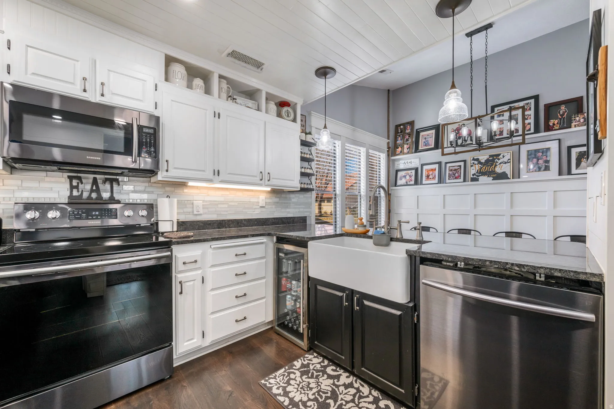 Kitchen featuring stainless steel appliances, white cabinets, dark cabinetry, dark stone counters, and wooden ceiling