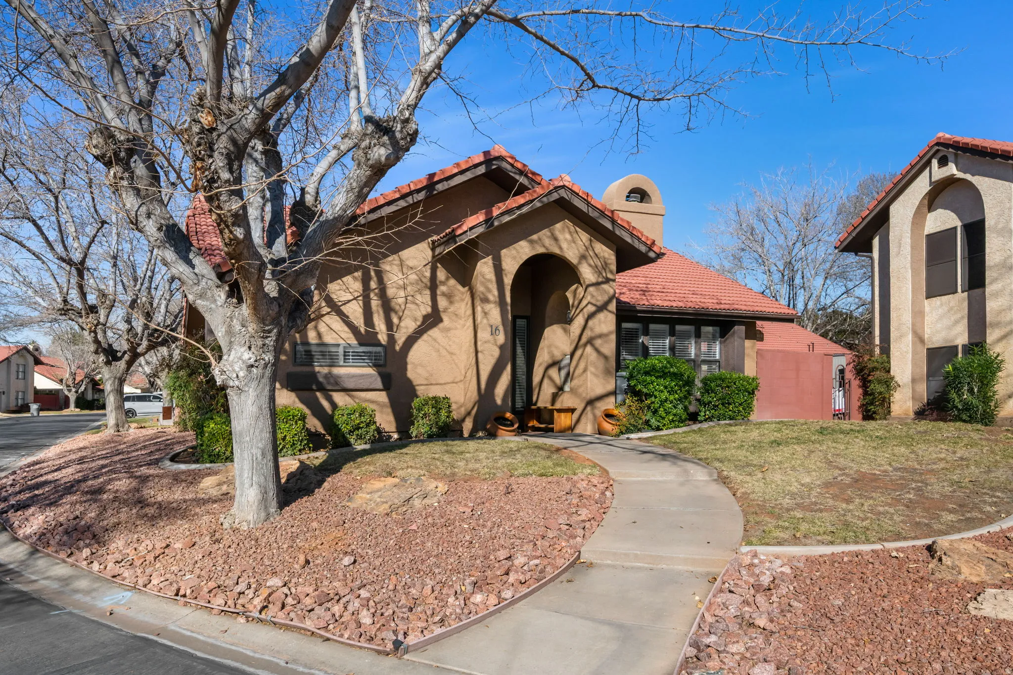 Mediterranean / spanish-style home with a tile roof, stucco siding, a front yard, and a chimney