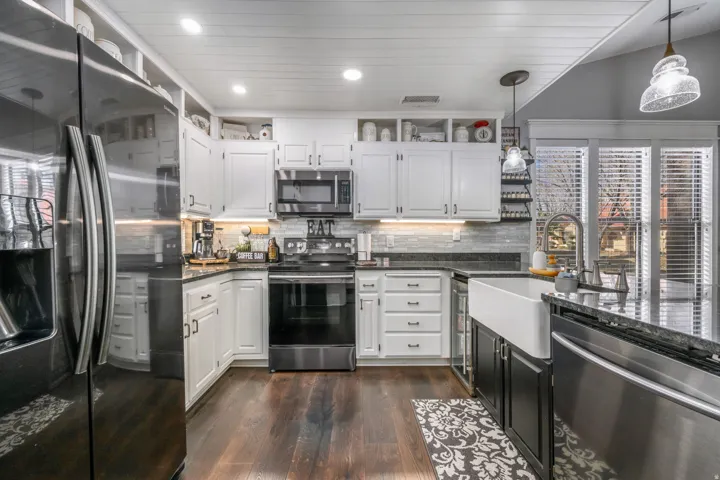 Kitchen featuring stainless steel appliances, open shelves, white cabinetry, dark cabinets, and recessed lighting