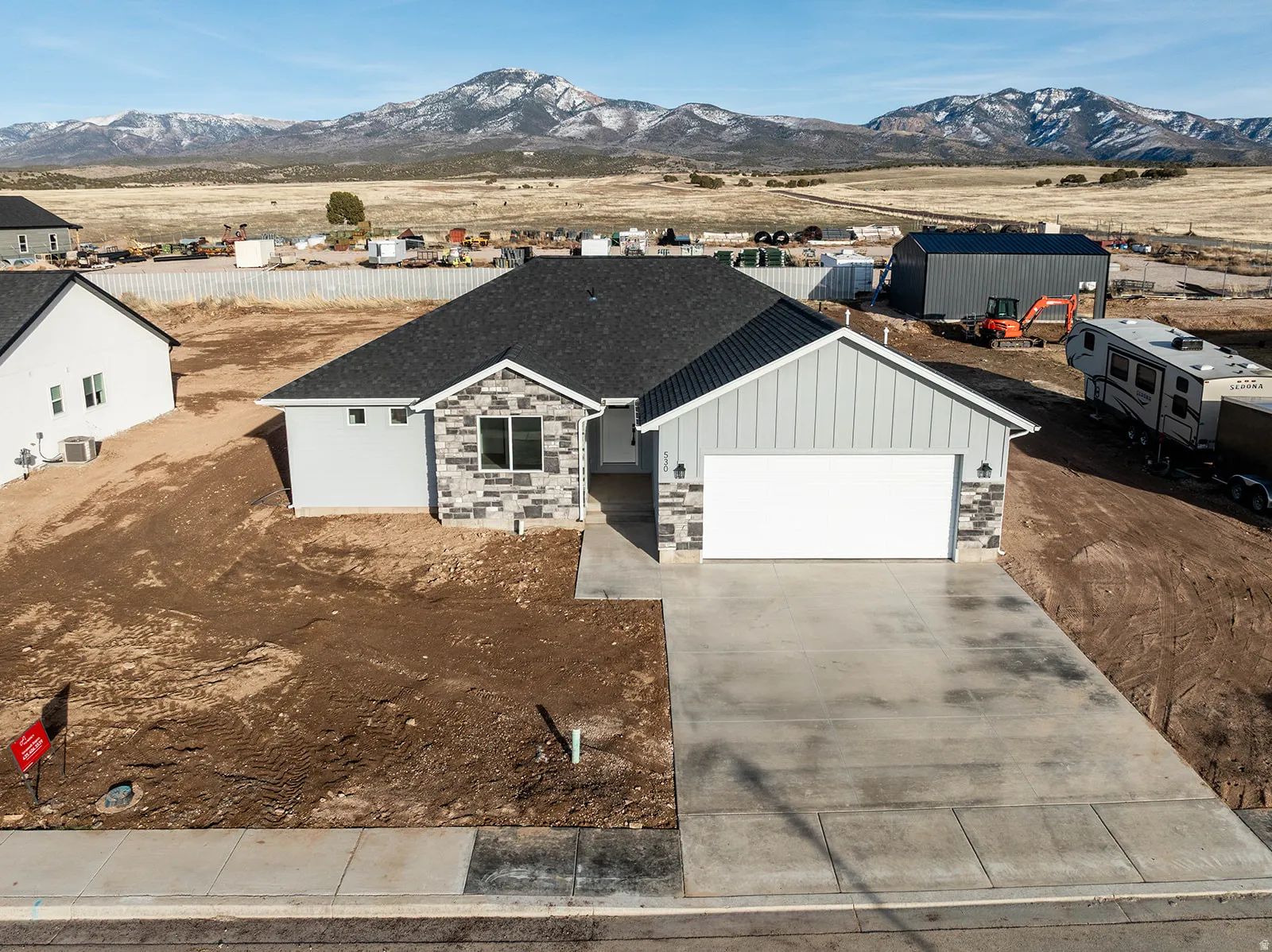 View of front facade with board and batten siding, a garage, concrete driveway, and stone siding