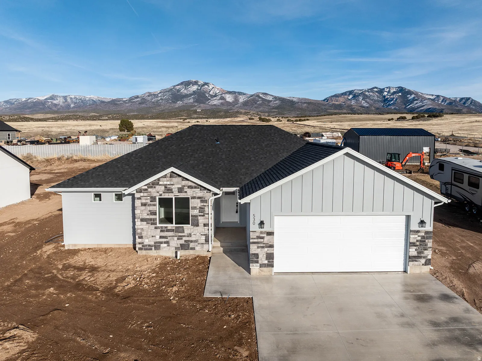 View of front facade with an attached garage, stone siding, board and batten siding, and driveway