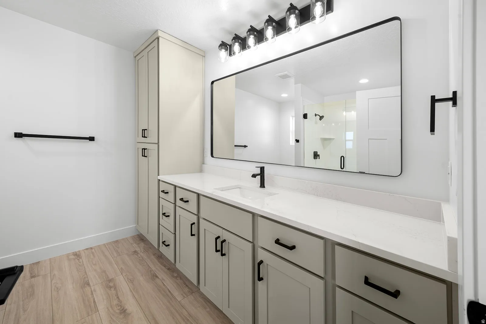 Bathroom featuring light wood finished floors, vanity, and a stall shower