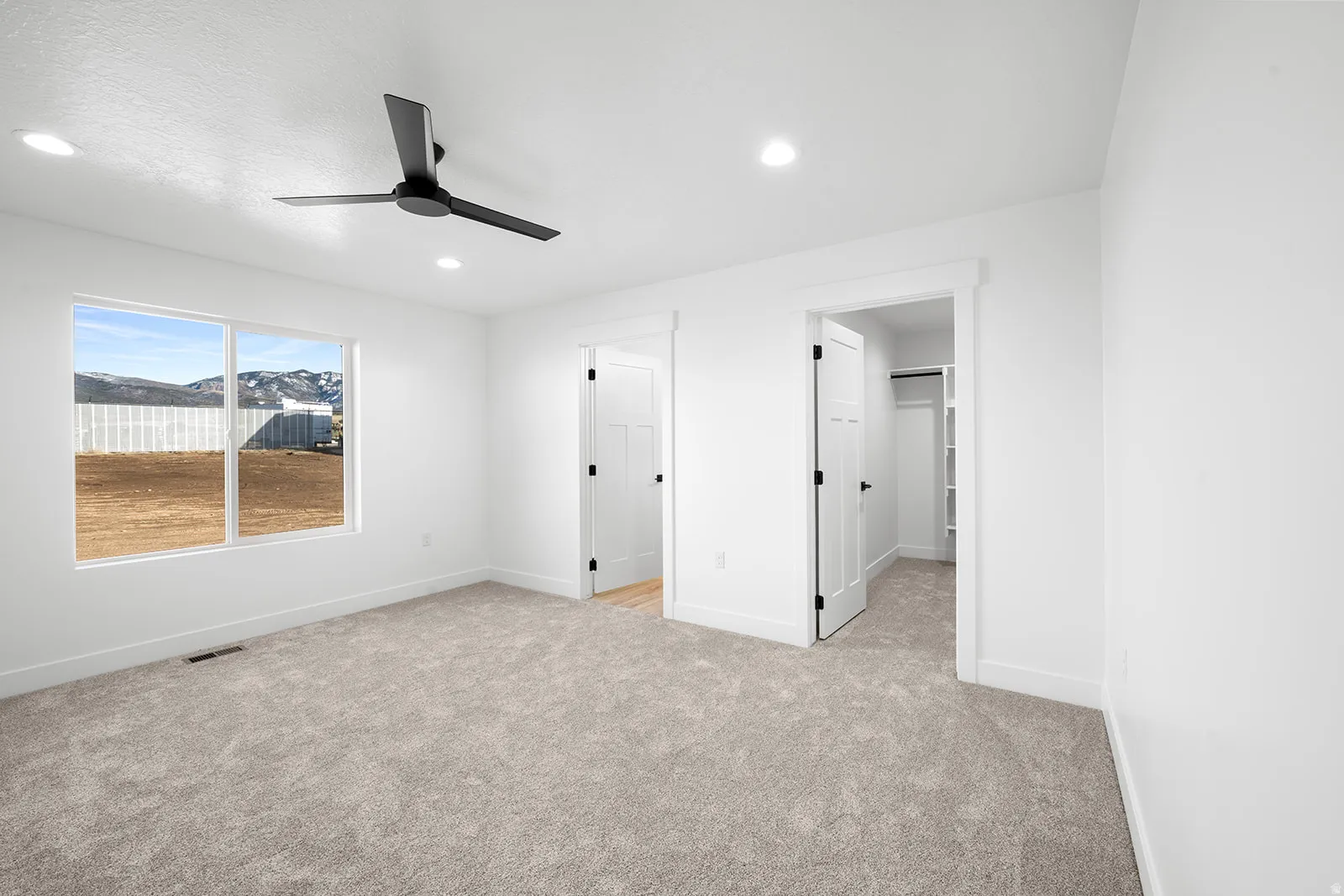Unfurnished bedroom with a spacious closet, light colored carpet, a ceiling fan, and recessed lighting
