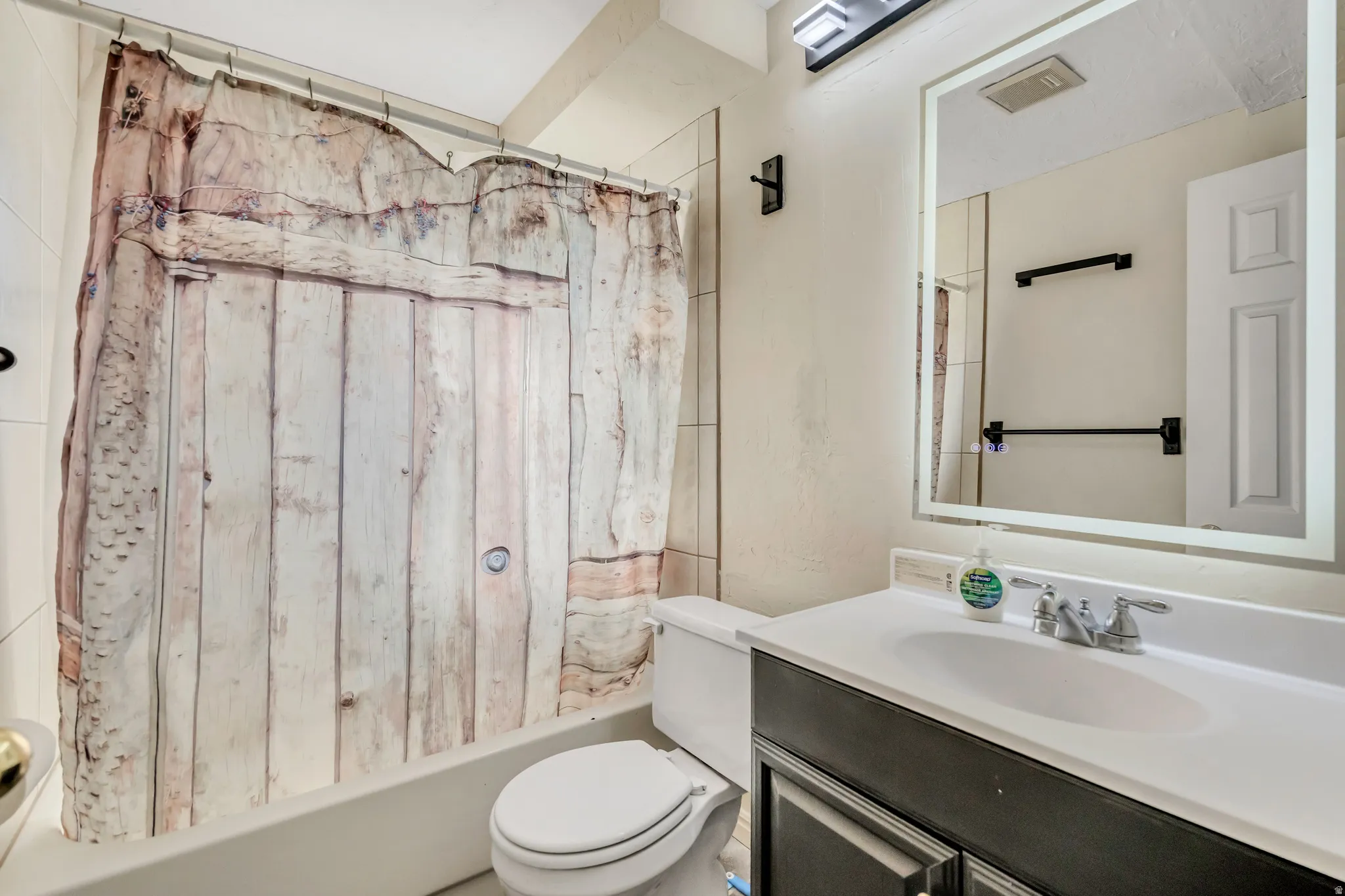 Bathroom featuring shower / bath combination with curtain and vanity