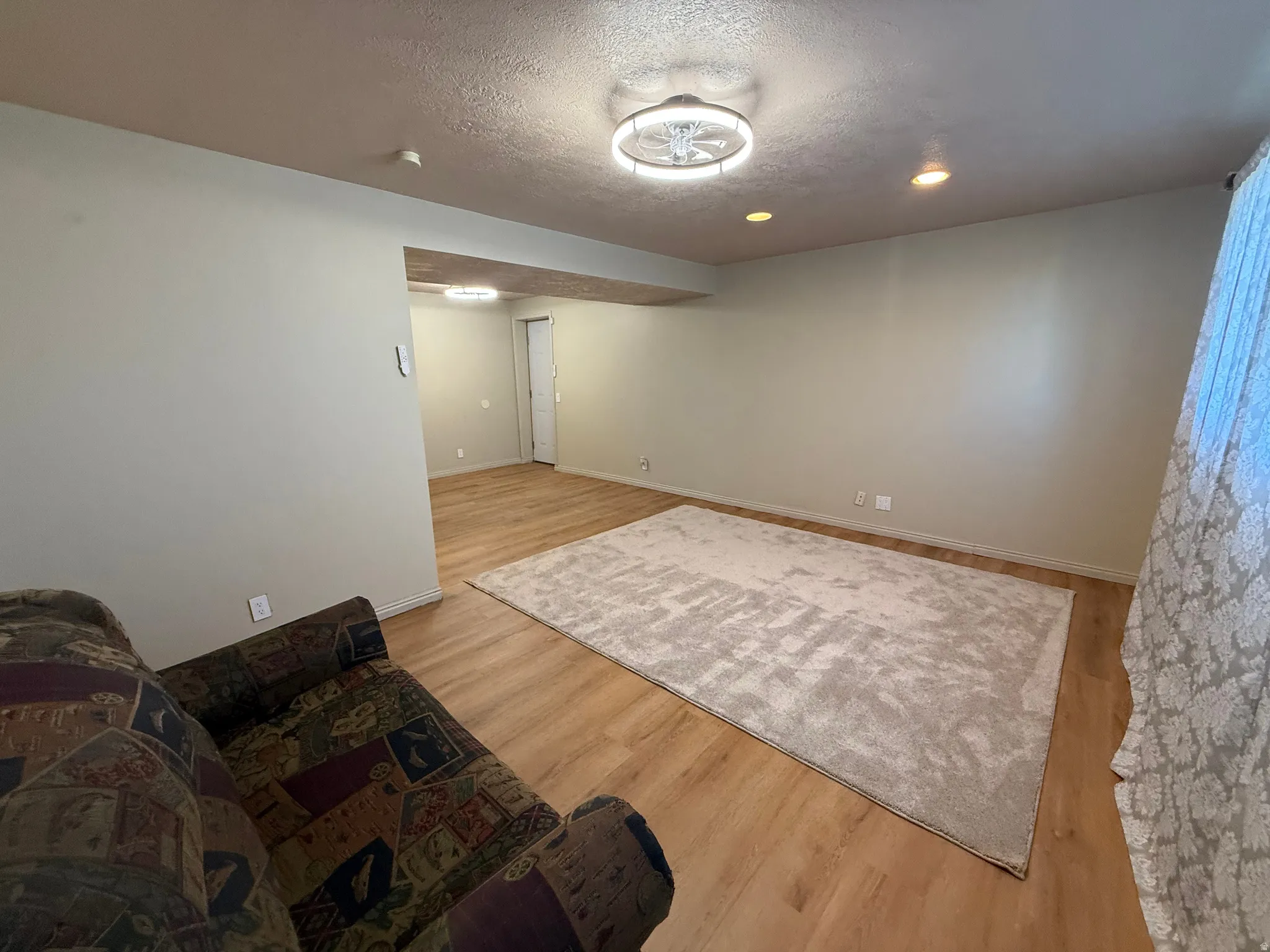 Spacious room featuring wood-finish flooring, light neutral wall paint, and a decorative ceiling light fixture