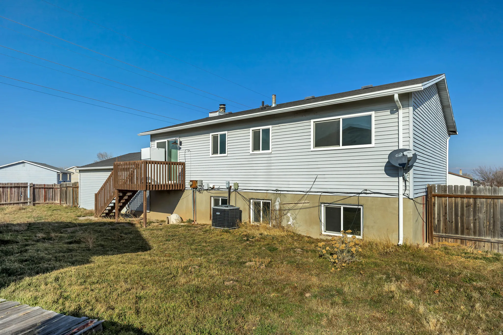 Rear view of house featuring a fenced backyard, stairs, and a wooden deck