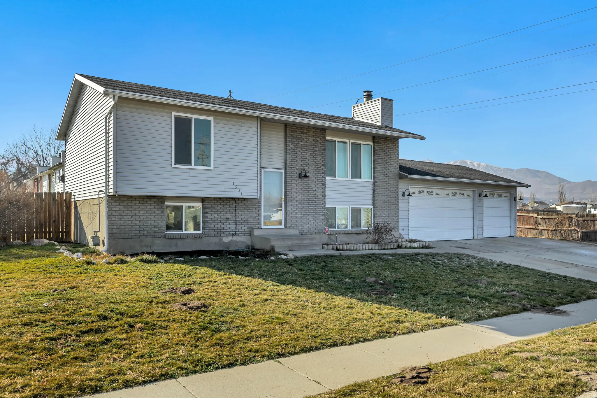 Bi-level home with a chimney, brick siding, concrete driveway, an attached garage, and a mountain view