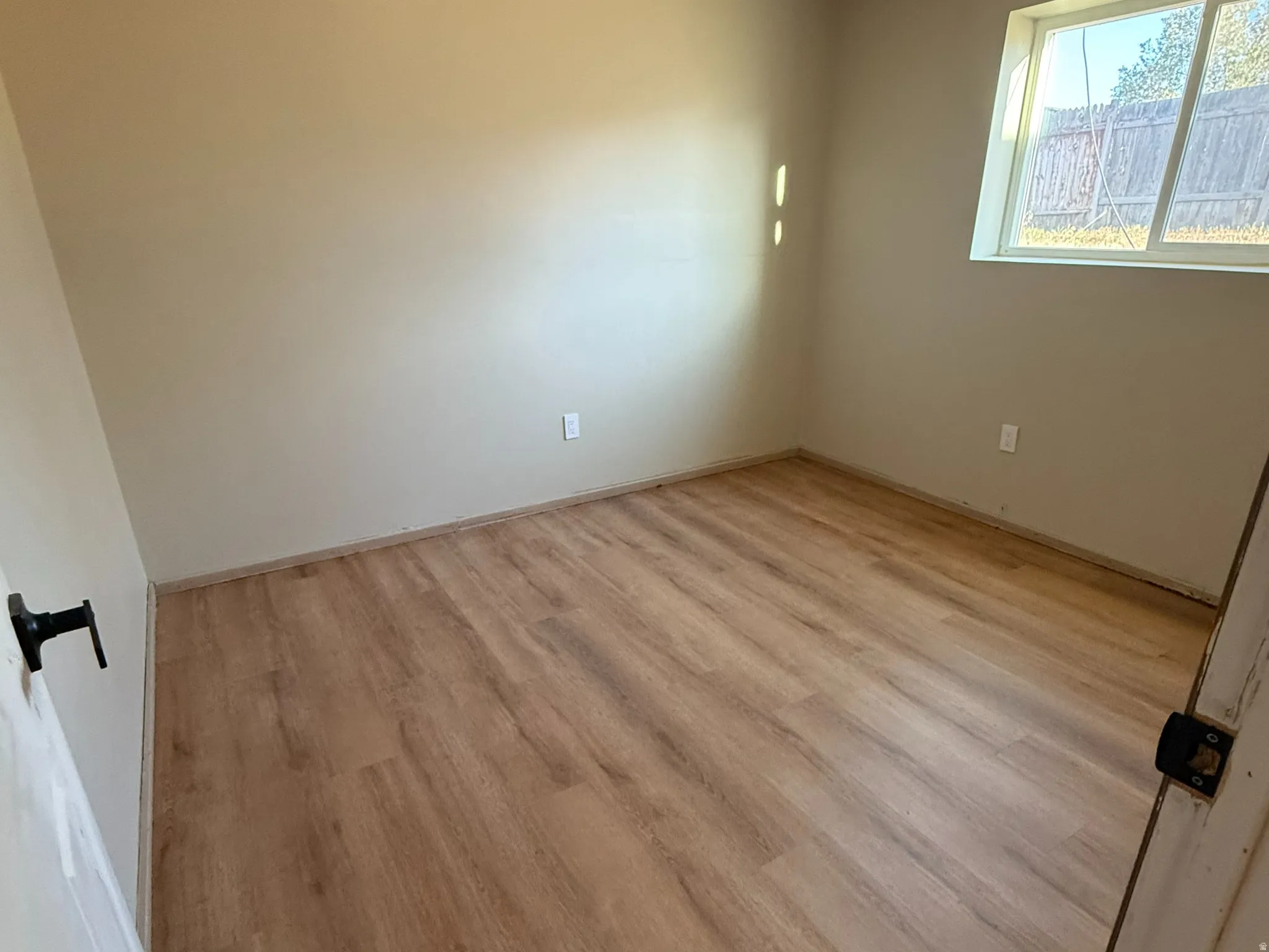 Room featuring wood-finish flooring, a window with exterior views, and a modern ceiling light fixture