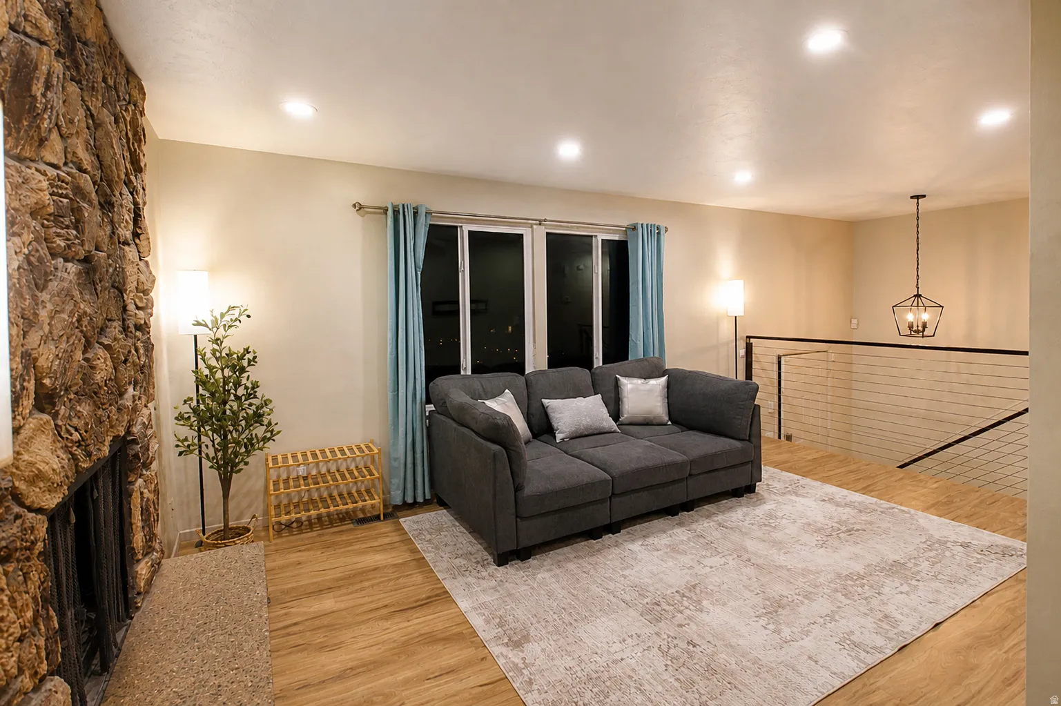 Living area with light wood-style flooring, hanging lights, and a fireplace
