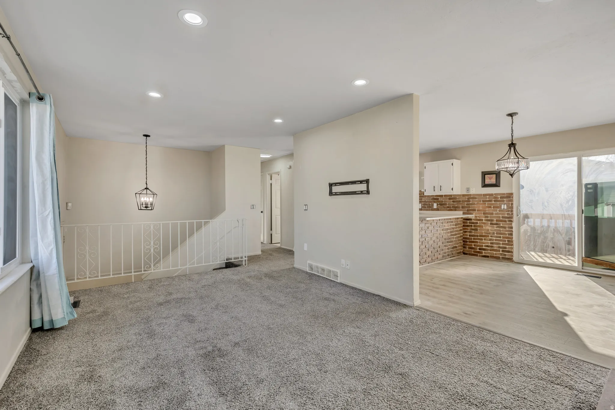 Unfurnished living room with a chandelier, light colored carpet, and recessed lighting