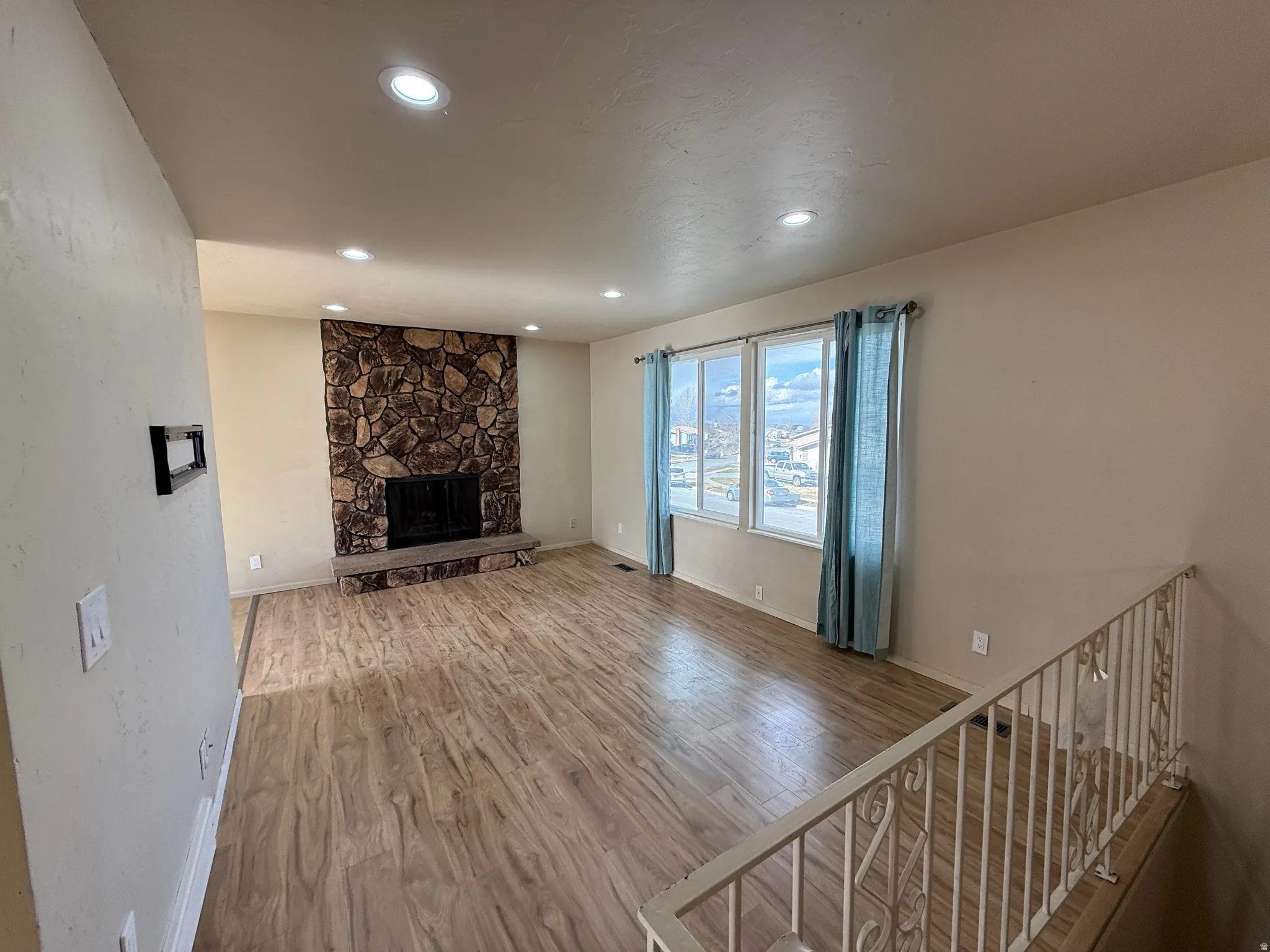 Unfurnished living room featuring wood finished floors, a fireplace, and recessed lighting