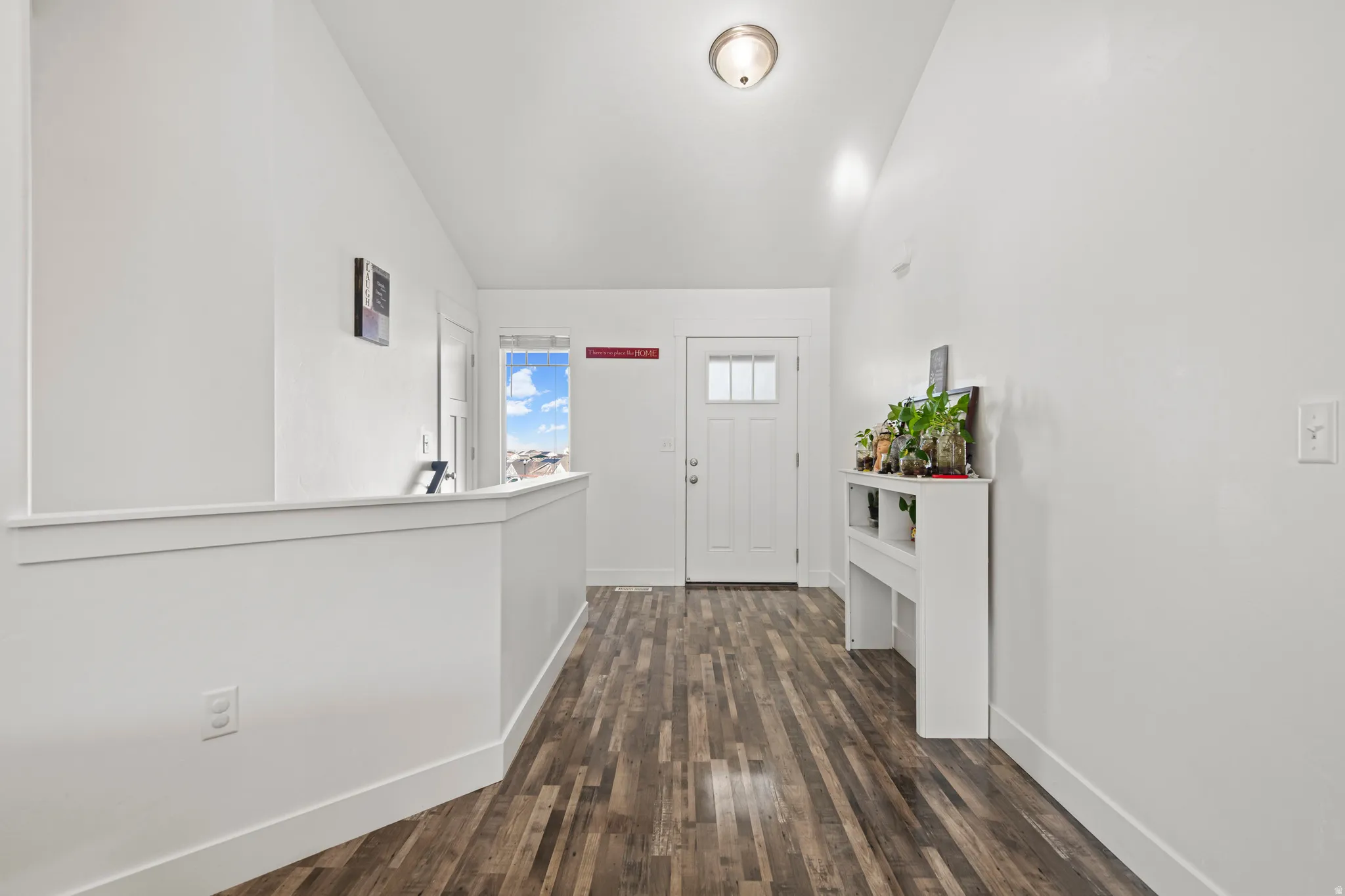 Entryway featuring dark wood-style flooring and vaulted ceiling