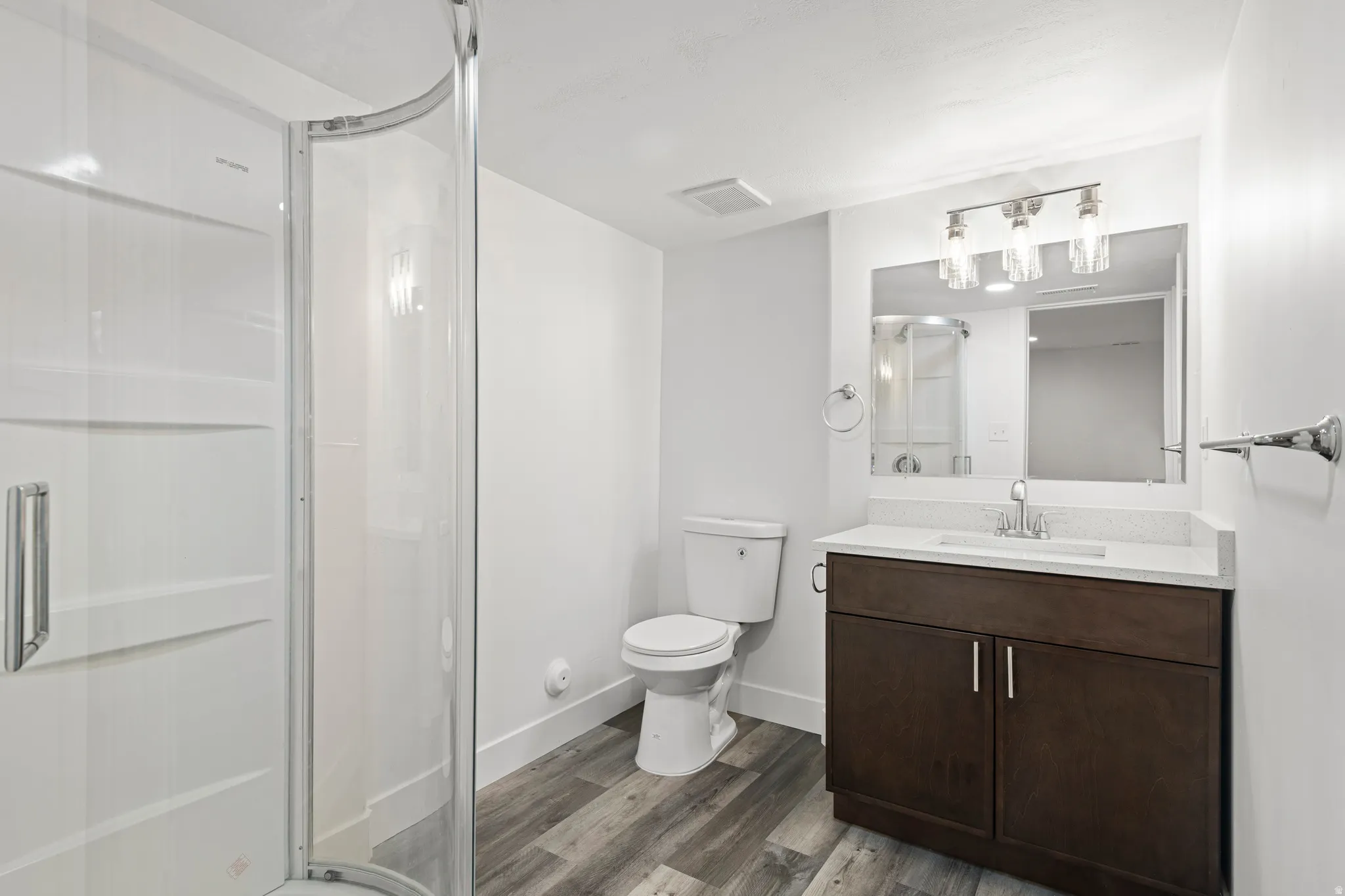 Full bath with vanity, a shower stall, and dark wood-style floors