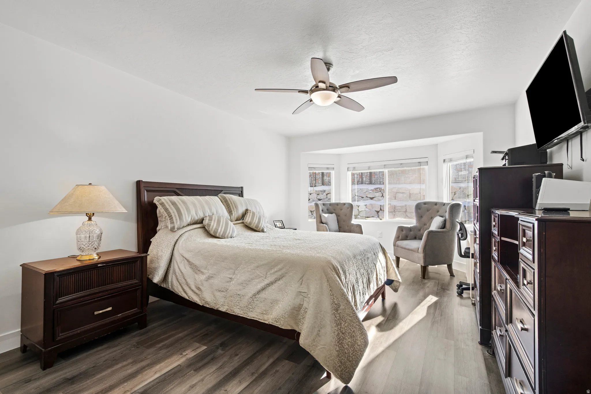 Bedroom with wood finished floors, a ceiling fan, and a textured ceiling
