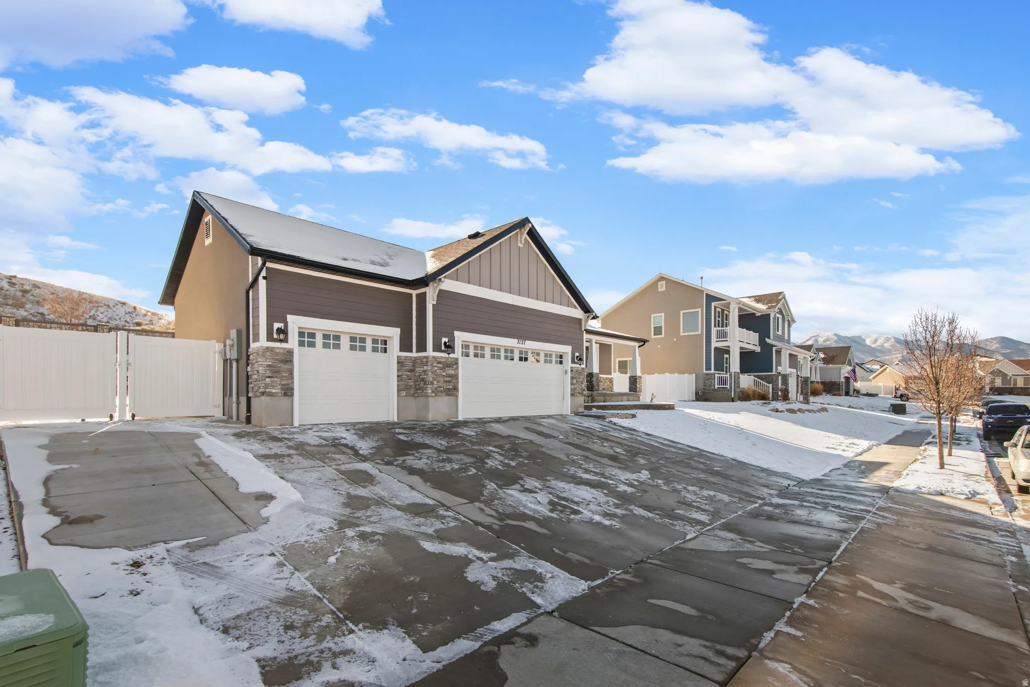 View of front of house featuring a residential view, stone siding, board and batten siding, driveway, and a garage