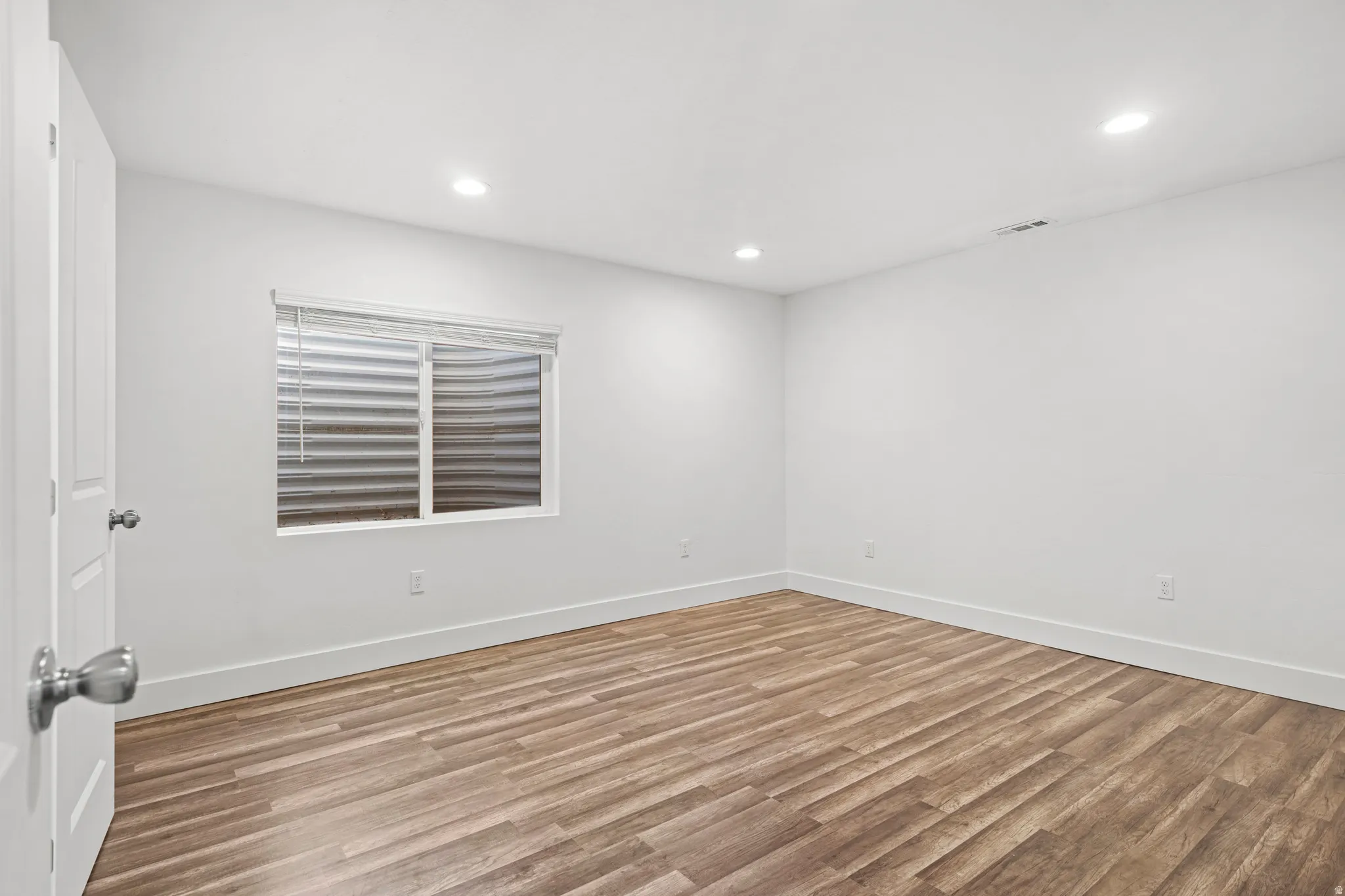 Empty room with light wood-type flooring and recessed lighting