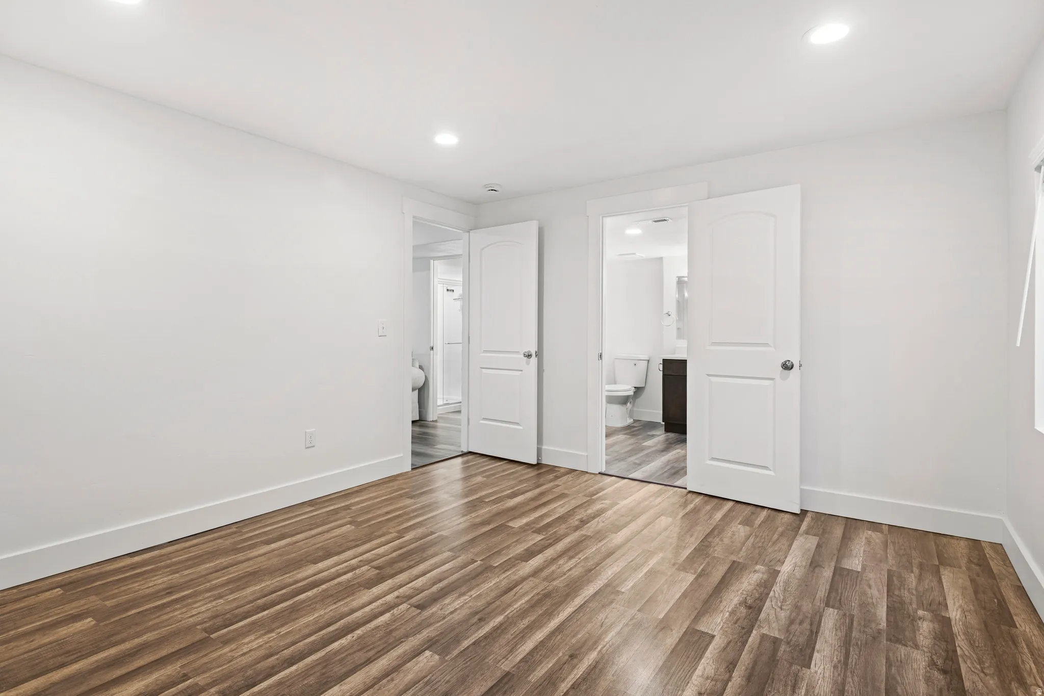 Unfurnished bedroom with wood finished floors, recessed lighting, and connected bathroom