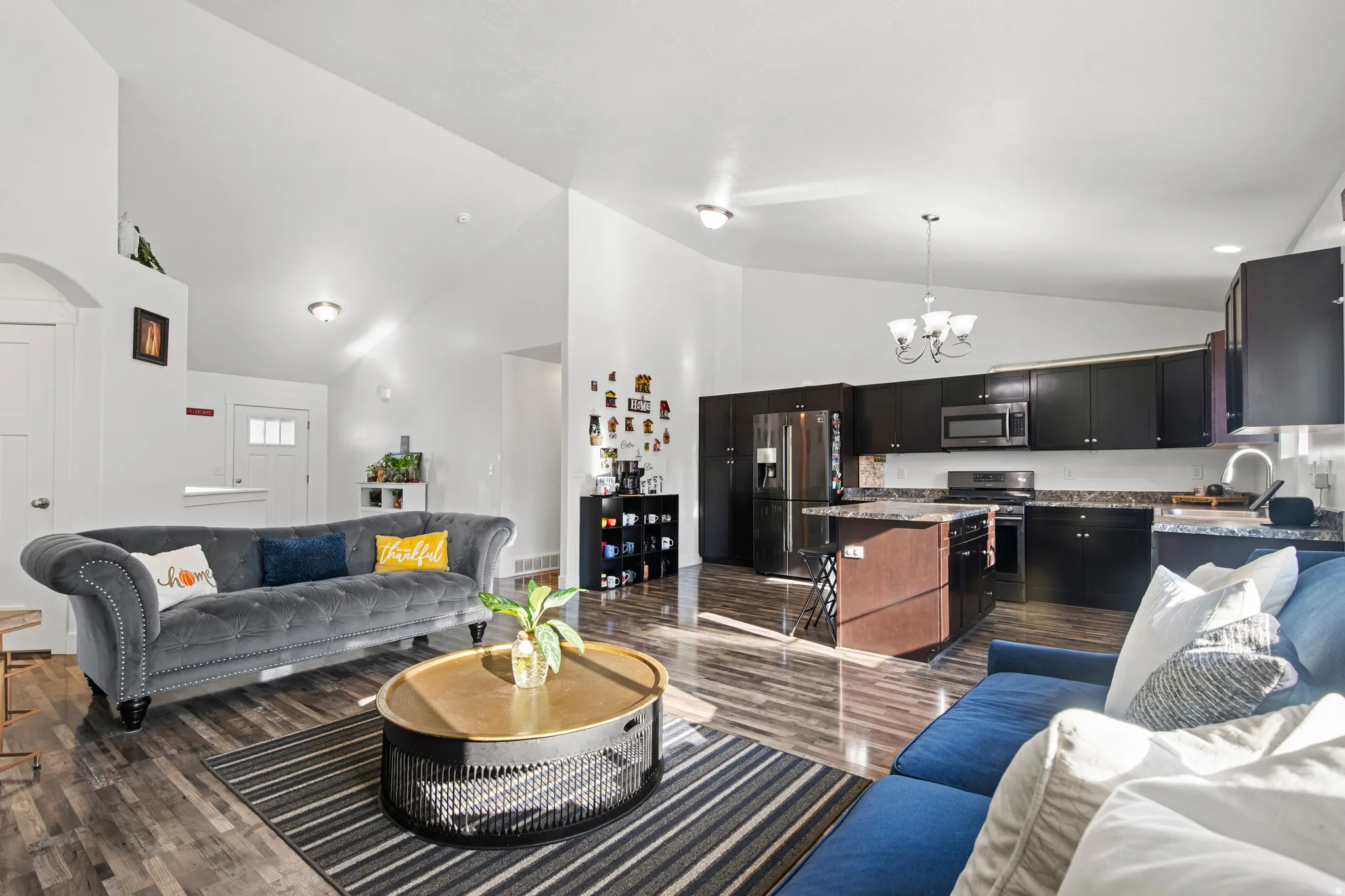 Living area with high vaulted ceiling, a chandelier, and dark wood-style flooring