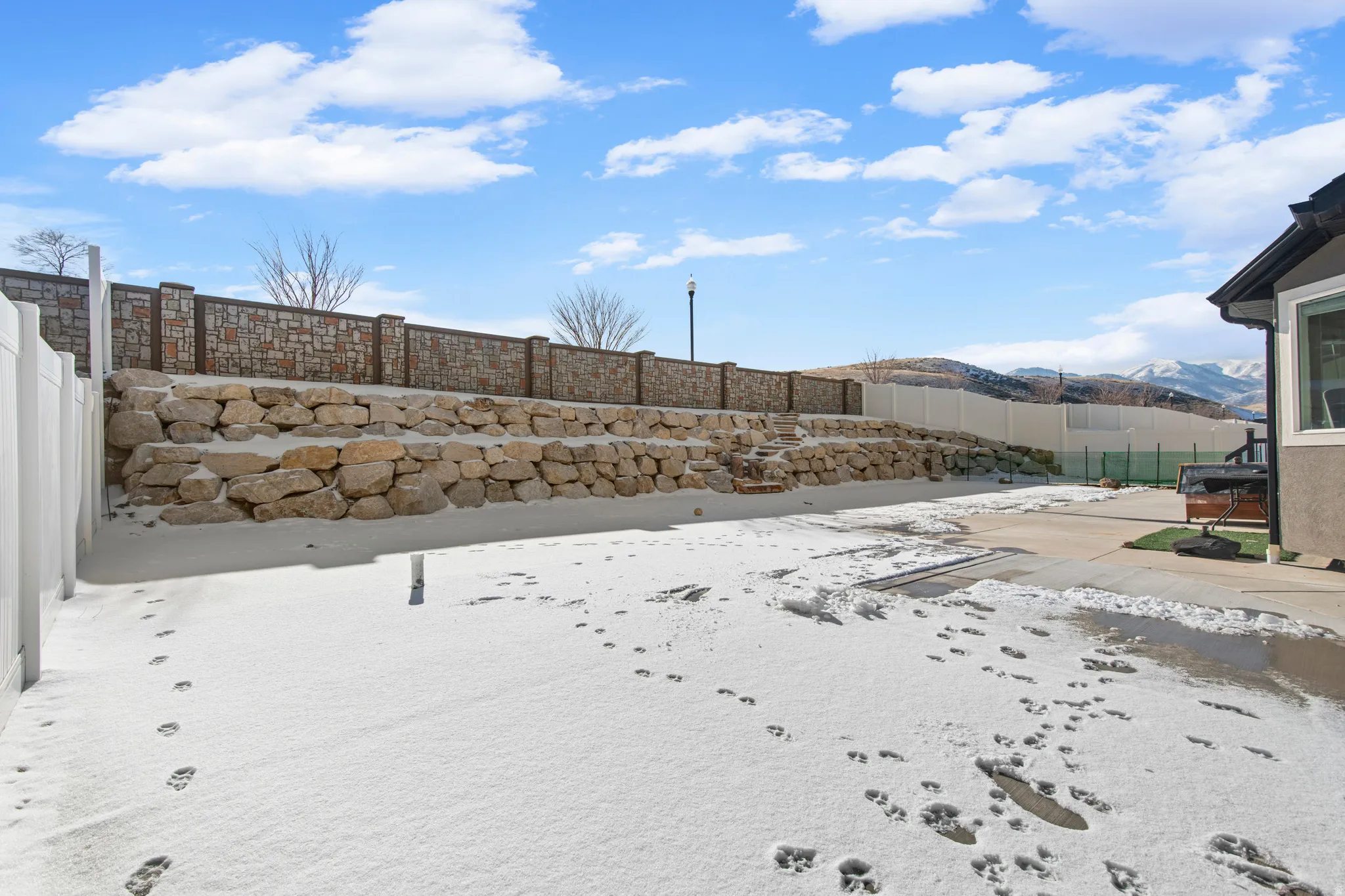 Yard covered in snow with a fenced backyard and a mountain view