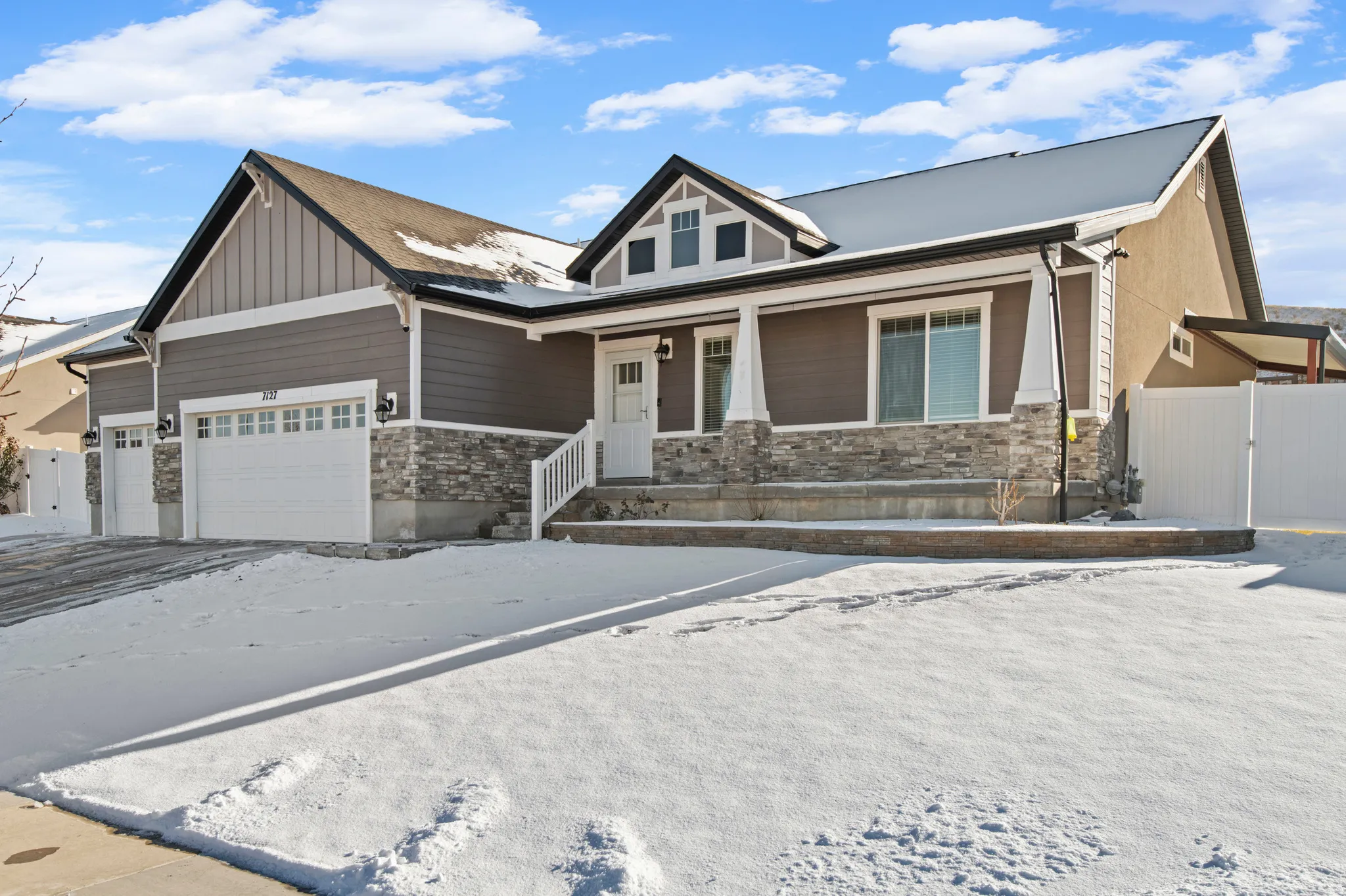 Craftsman house with stone siding, covered porch, a garage, and board and batten siding