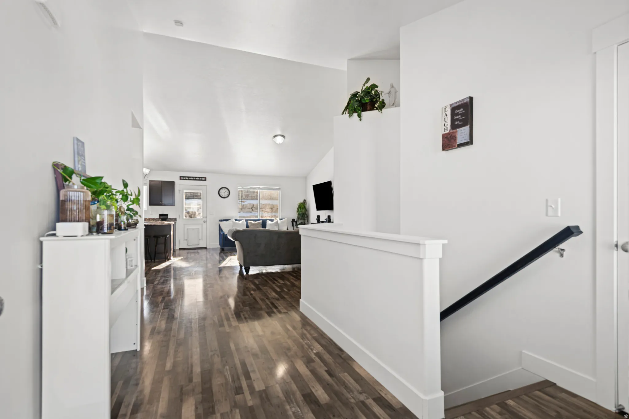 Corridor featuring an upstairs landing, dark wood-style flooring, and high vaulted ceiling