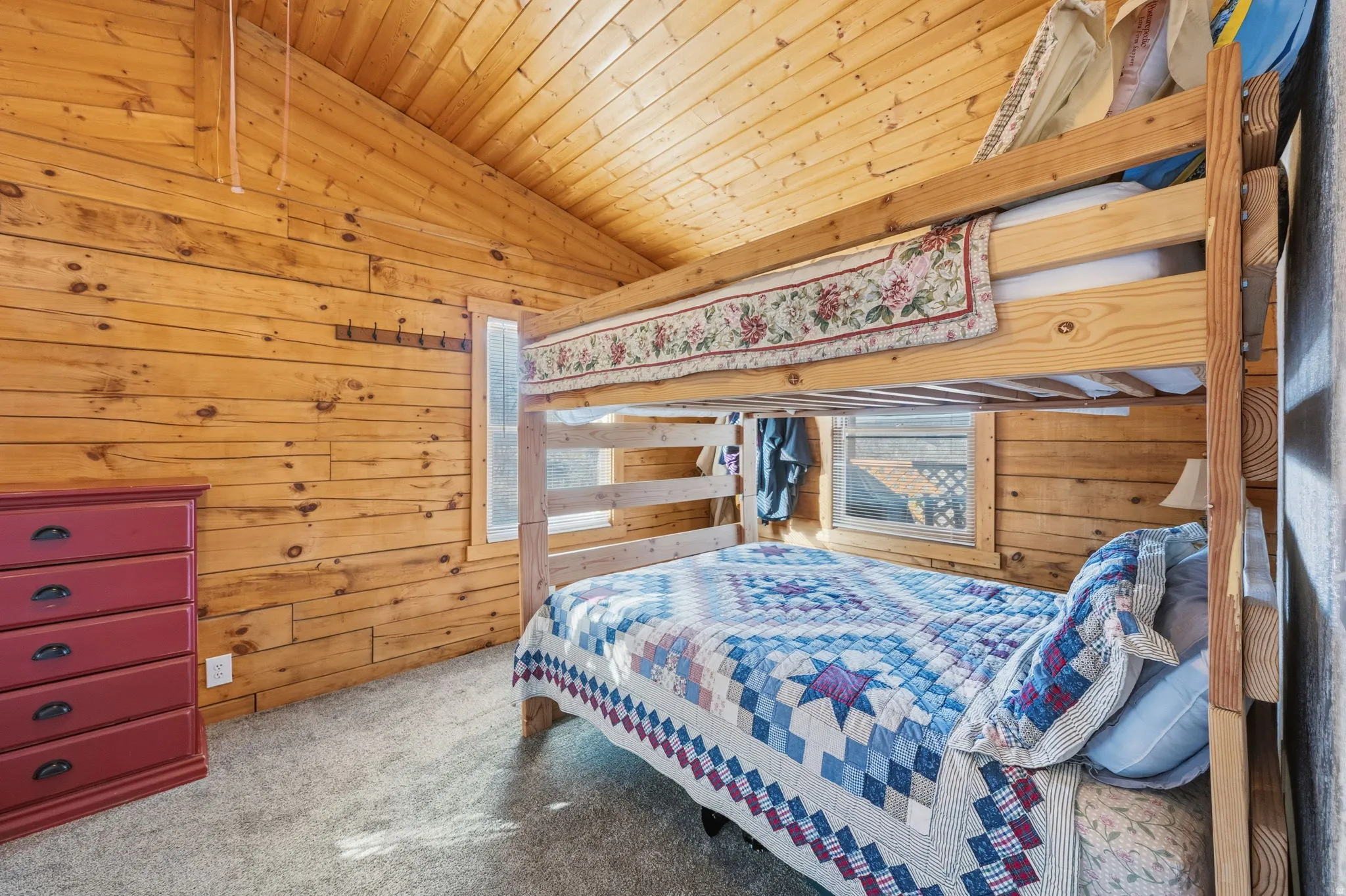 Bedroom featuring wood ceiling, lofted ceiling, wooden walls, carpet, and multiple windows