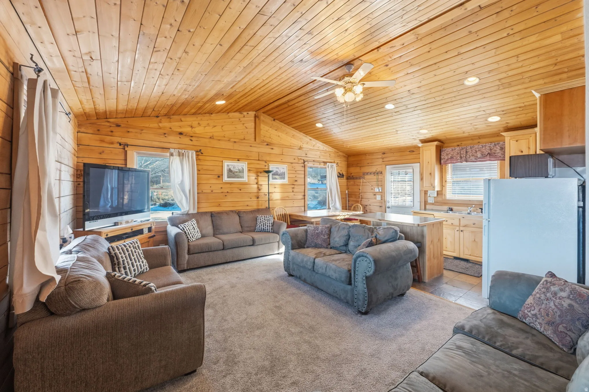 Living room with lofted ceiling, wood ceiling, healthy amount of natural light, recessed lighting, and a ceiling fan