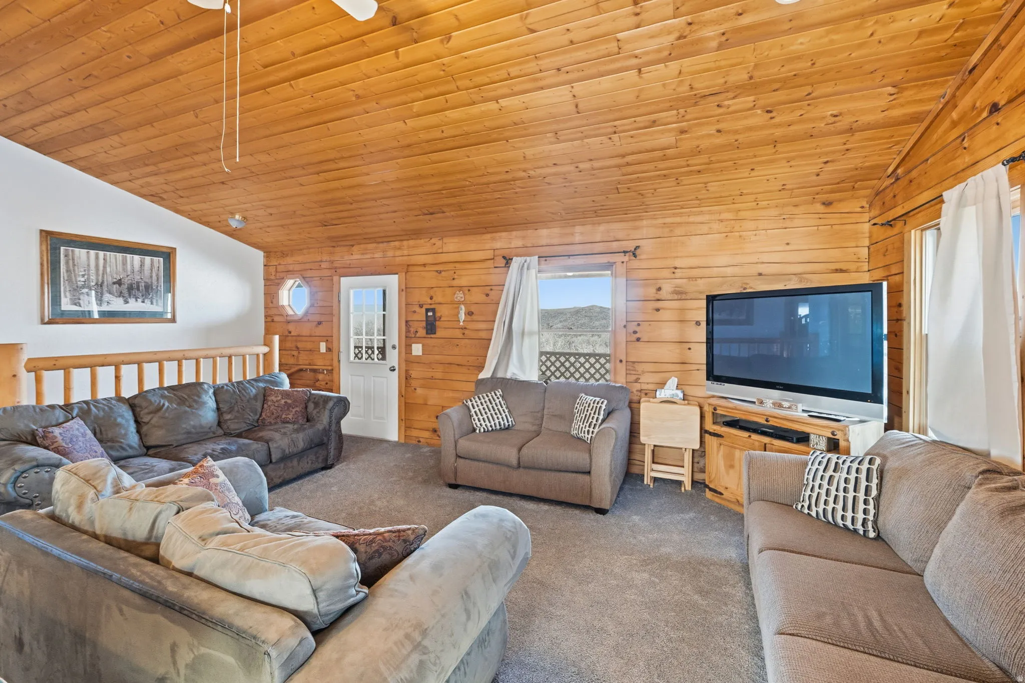 Living room with vaulted ceiling, carpet flooring, wooden ceiling, and wooden walls