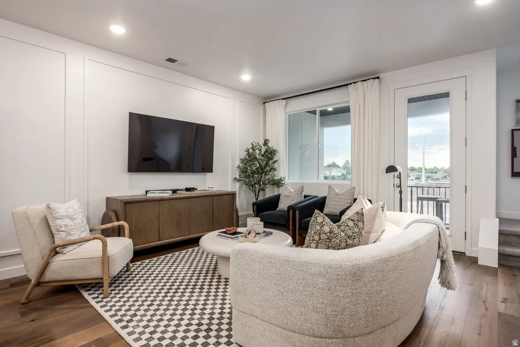 Living room featuring dark wood-style flooring, recessed lighting, and a decorative wall