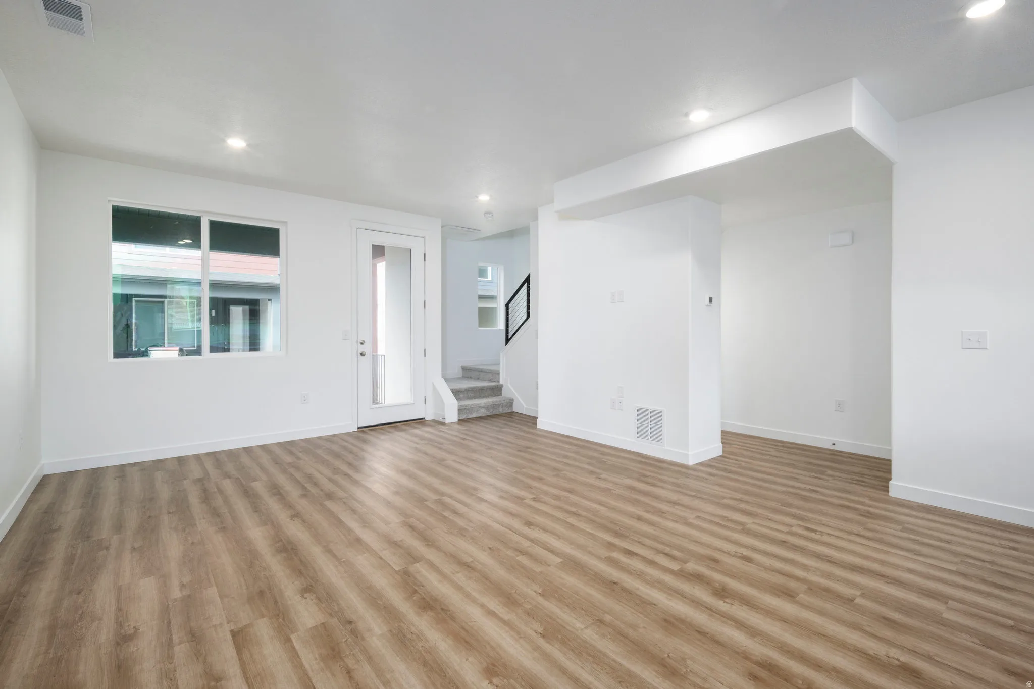 Unfurnished living room featuring stairs, recessed lighting, and light wood-type flooring