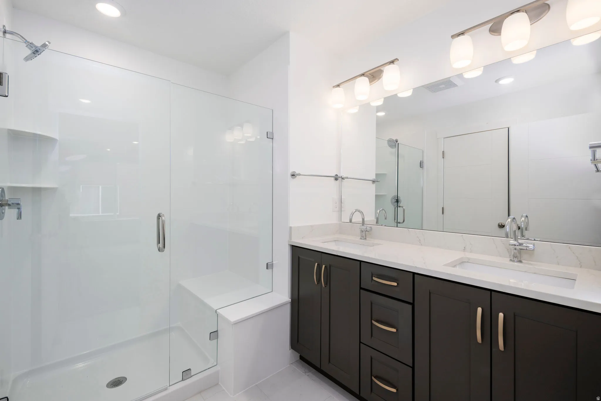 Full bathroom with double vanity, a shower stall, and recessed lighting