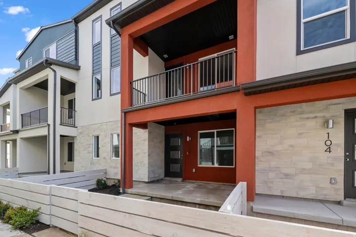 Rear view of property with stone siding, stucco siding, and a balcony