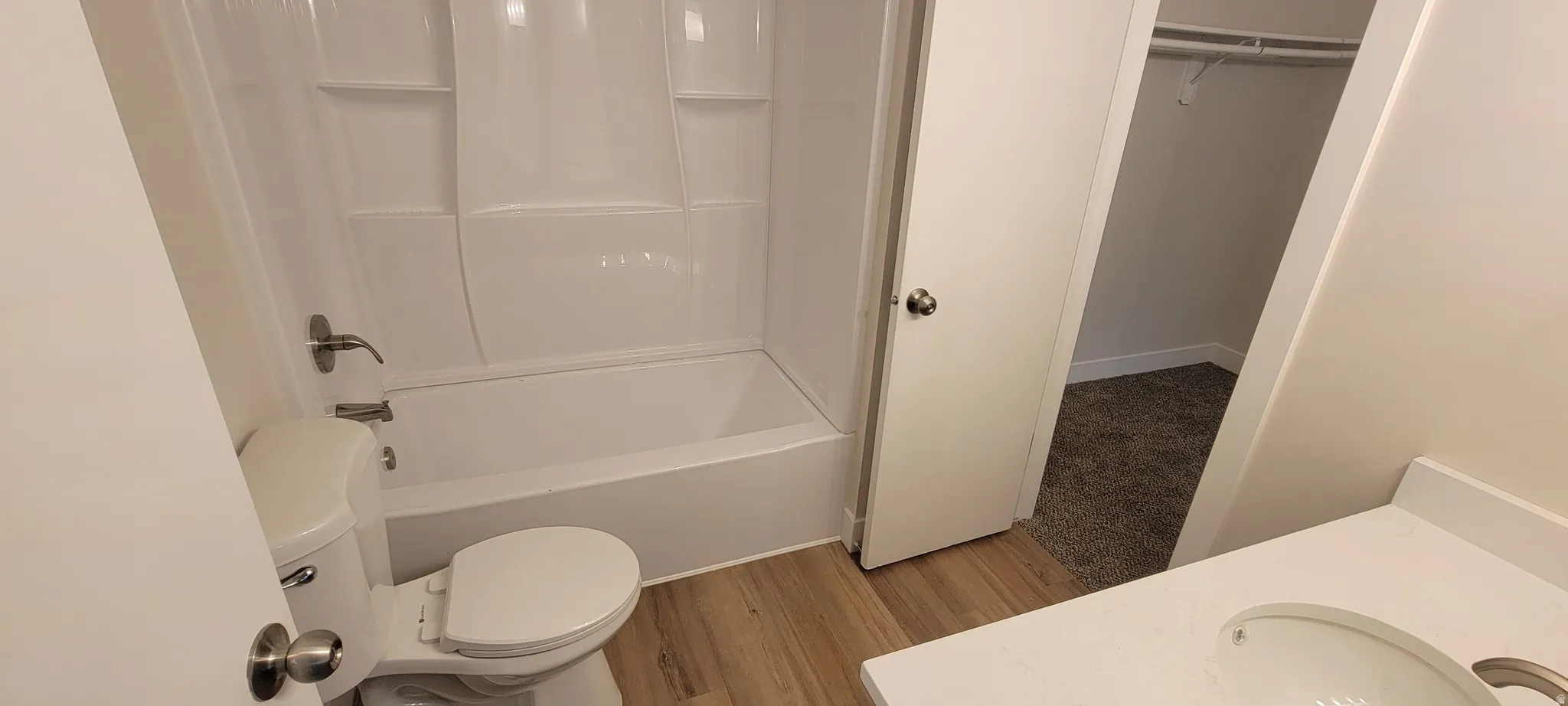 Full bathroom featuring vanity, a walk in closet, shower / washtub combination, and light wood finished floors