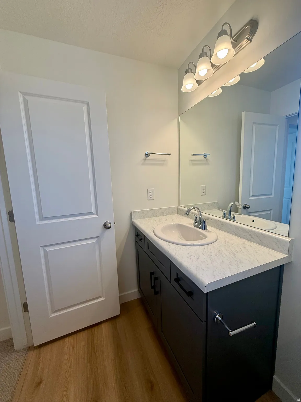 Bathroom featuring vanity, light wood-style flooring, and a textured ceiling