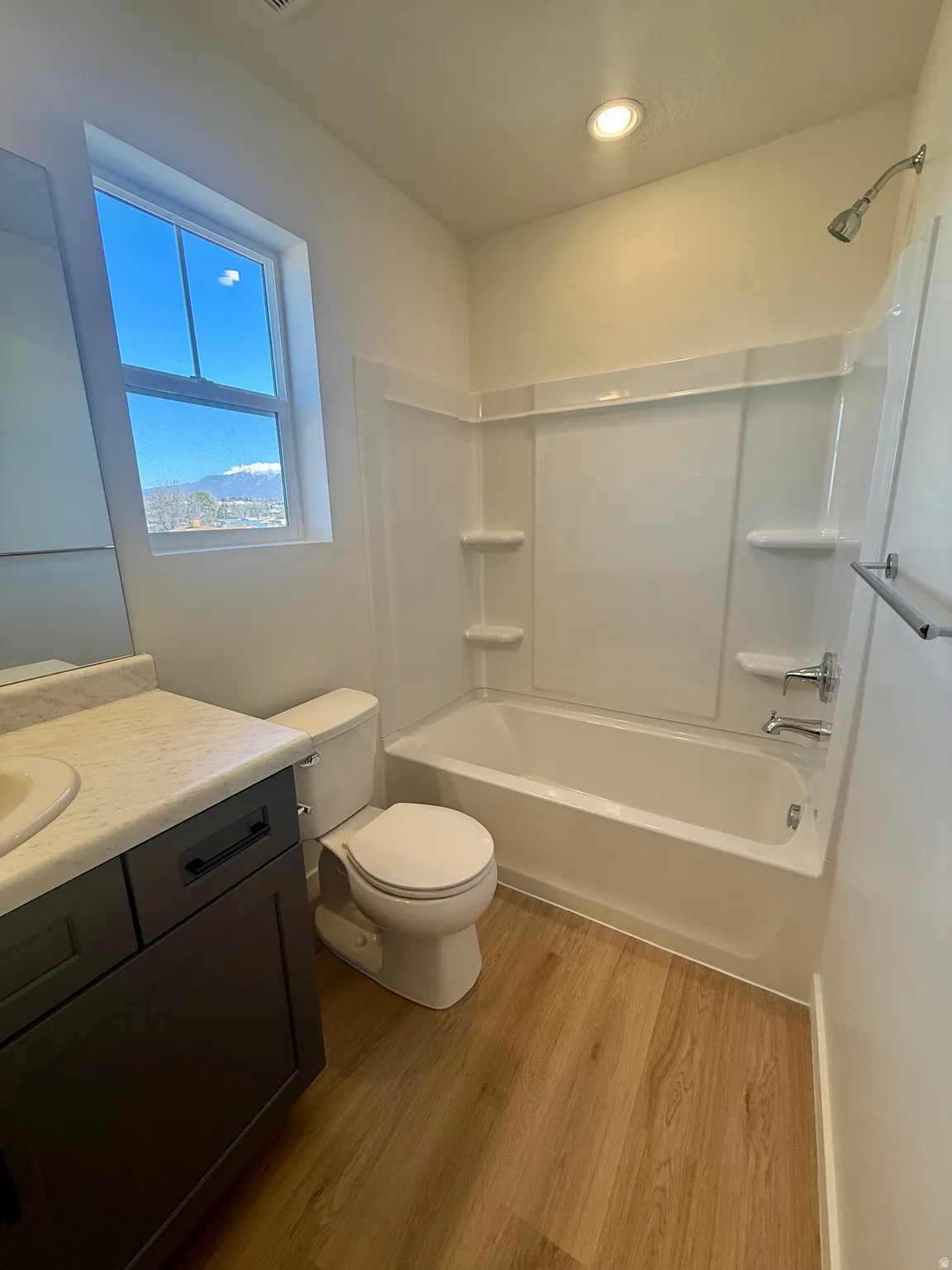 Full bath featuring vanity, shower / tub combination, and light wood-style flooring